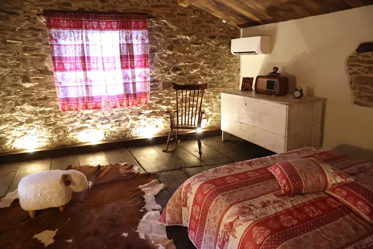 Camera matrimoniale con pareti in pietra e pavimento in legno di castagno